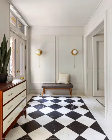 a living room with a black white checkered floor with a gaming machine and wooden floor