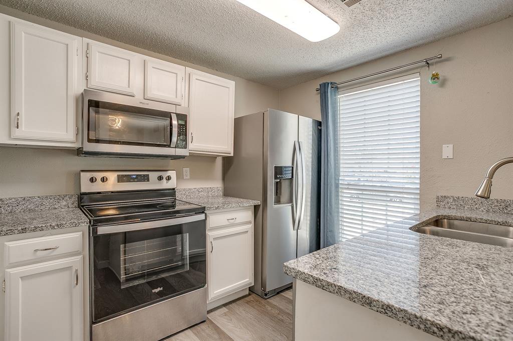 7312 Strawberry Way Fort Worth, TX 76137 - Photo 20 of 40 a kitchen with granite countertop wooden cabinets sink and stainless steel appliances
