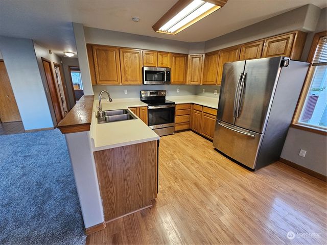 a kitchen with granite countertop wooden floors a sink and appliances