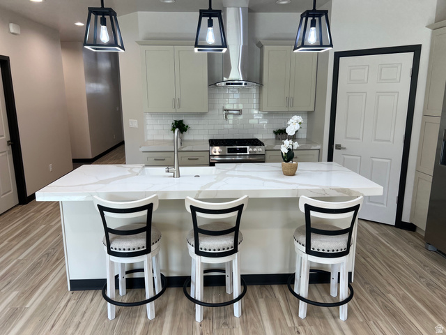 160 200 West Henefer, UT 84033 - Photo 7 of 25 Kitchen featuring a large central island with a built-in sink, light-colored cabinetry, stainless steel appliances, a subway tile backsplash, and wood-finish flooring