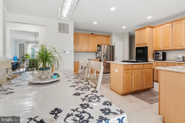 a kitchen with stainless steel appliances kitchen island granite countertop a refrigerator a stove a sink dishwasher with a dining table and chairs with wooden floor