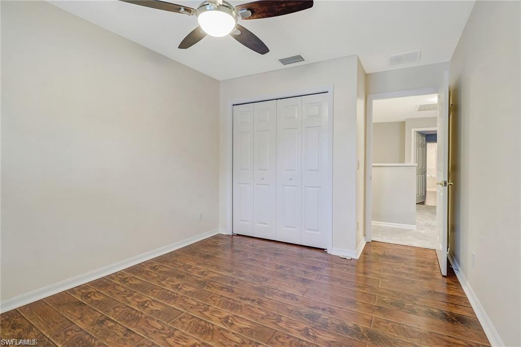 9801 Foxhall Way, Unit 4 Estero, FL 33928 - Photo 12 of 23 Unfurnished bedroom with dark wood-style flooring, a closet, and a ceiling fan