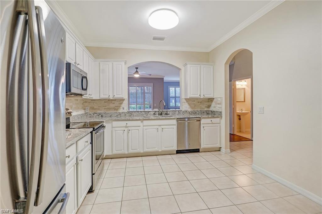 9801 Foxhall Way, Unit 4 Estero, FL 33928 - Photo 2 of 23 Kitchen featuring stainless steel appliances, white cabinets, ornamental molding, and light tile patterned floors