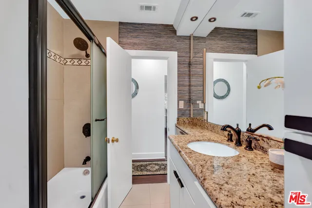 a bathroom with a sink double vanity granite tub shower and mirror
