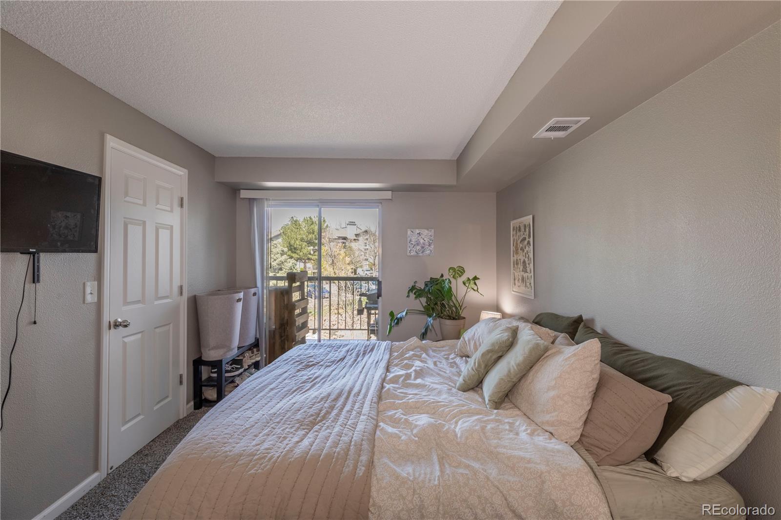 2575 South Syracuse Way, Unit M206 Denver, CO 80231 - Photo 13 of 24 a bedroom with a bed window and a flat screen tv