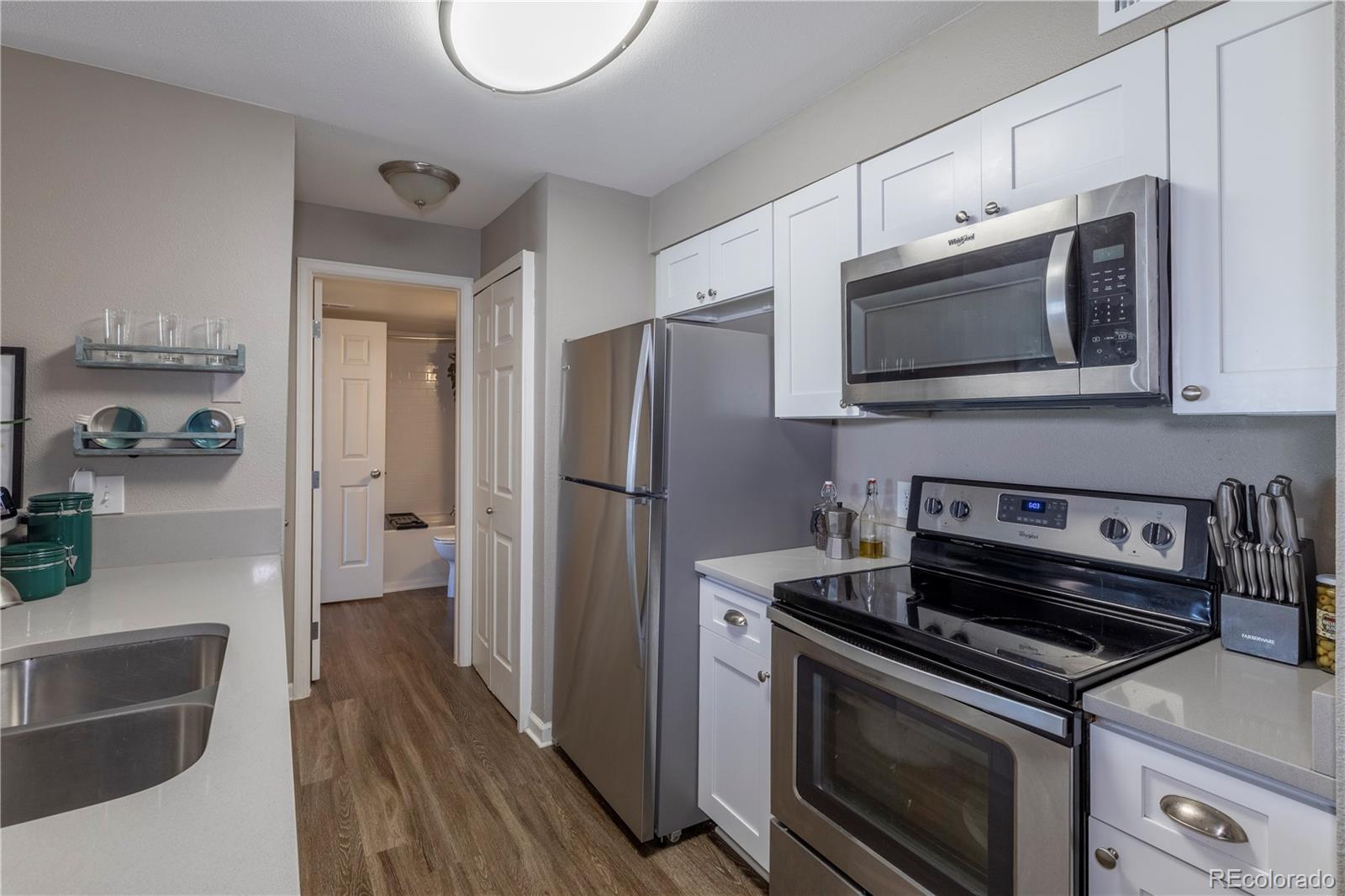 2575 South Syracuse Way, Unit M206 Denver, CO 80231 - Photo 5 of 24 a kitchen with granite countertop cabinets stainless steel appliances and wooden floor