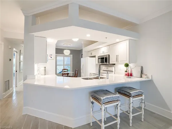 a large white kitchen with kitchen island a table and chairs in it