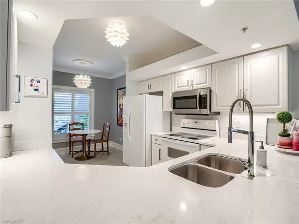 a kitchen with stainless steel appliances a stove a sink a microwave a dining table and chairs with wooden floor