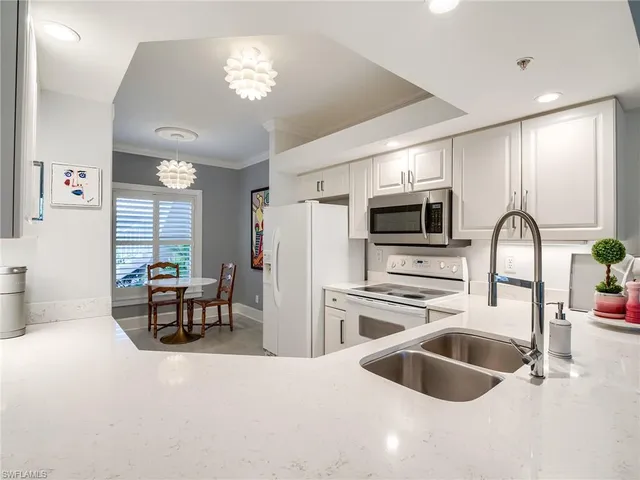 a kitchen with stainless steel appliances a stove a sink a microwave a dining table and chairs with wooden floor