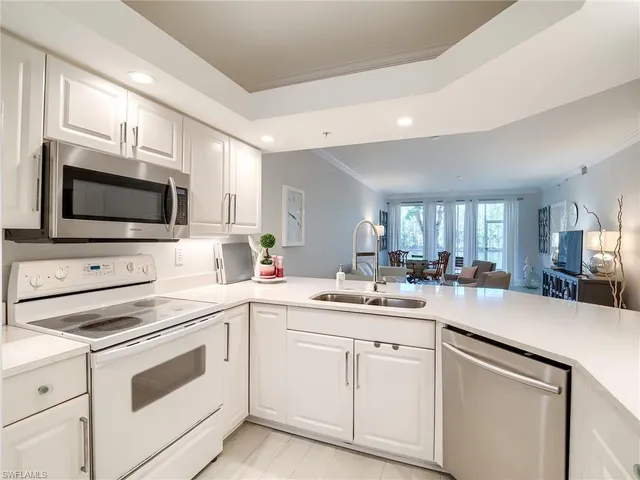 a kitchen with a sink white cabinets and white appliances