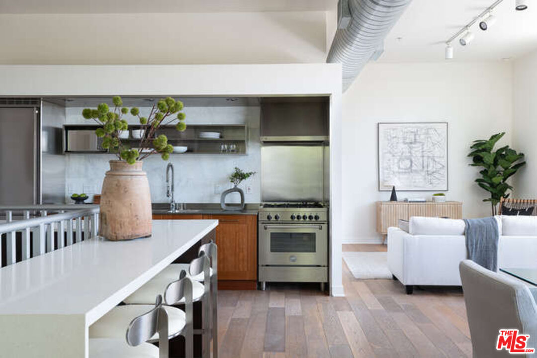 a kitchen with stainless steel appliances a white cabinets chair and a potted plant