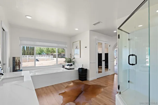 a large white bathroom with a tub shower and mirror