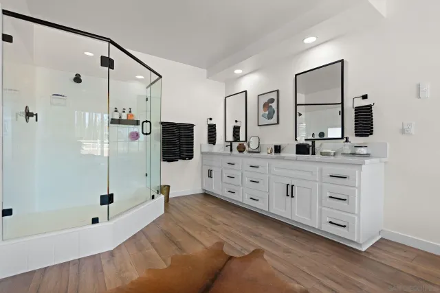 a spacious bathroom with double sink shower and mirror