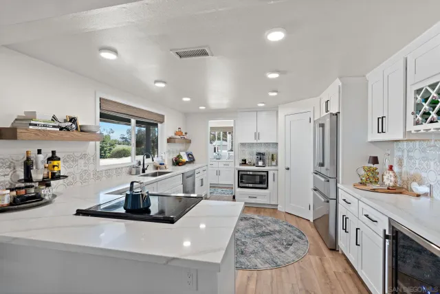 a kitchen with stainless steel appliances a sink a stove a refrigerator cabinets and wooden floor