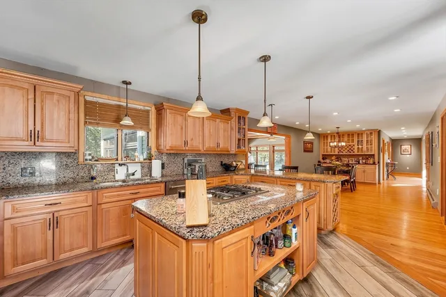a kitchen with stainless steel appliances granite countertop a sink a stove and a wooden floors