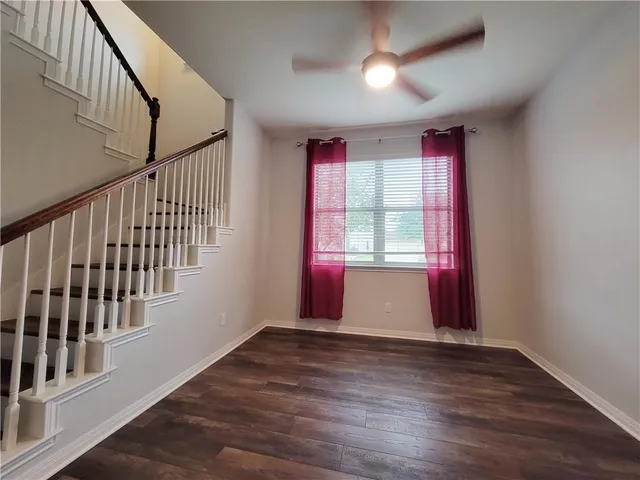 a view of an empty room with wooden floor and windows