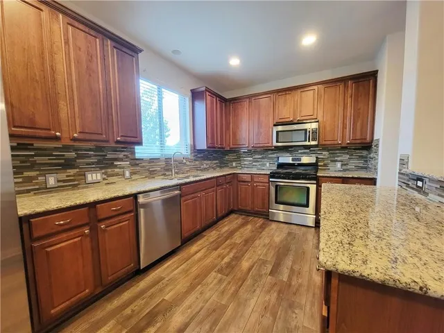 a kitchen with stainless steel appliances granite countertop wooden cabinets a stove top oven a sink and dishwasher