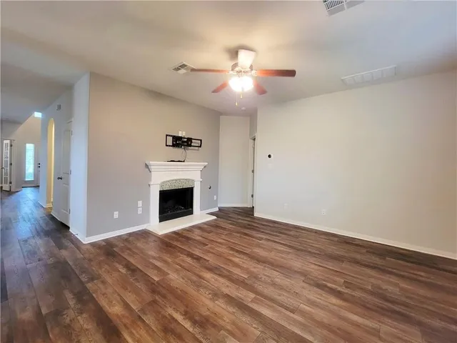 a view of an empty room with wooden floor fireplace and a window