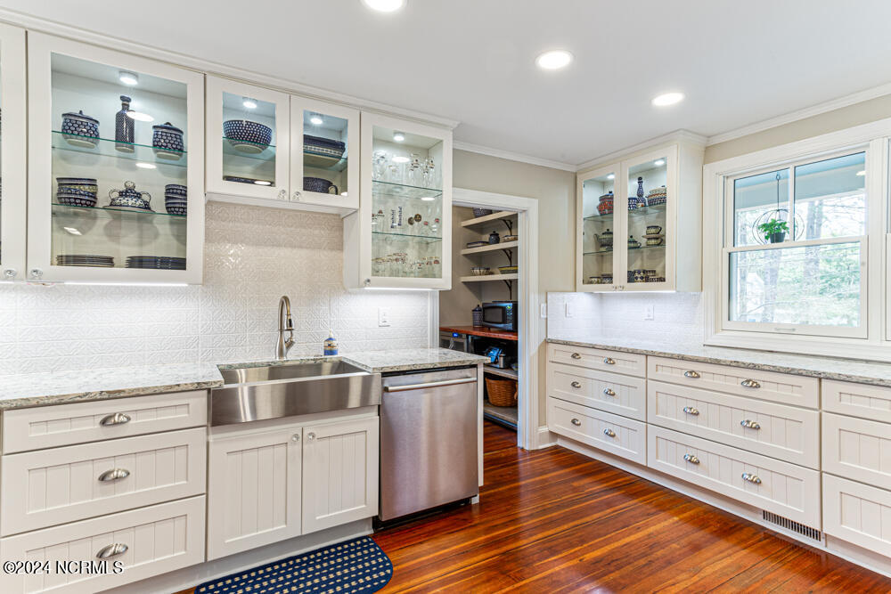 180 North Ridge Street Southern Pines, NC 28387 - Photo 36 of 72 Complete kitchen renovation with custom cabinetry with lighted glass upper cabinets, farm sink, Cambria quartz countertops, under cabinet lighting, and porcelain tile backsplash.