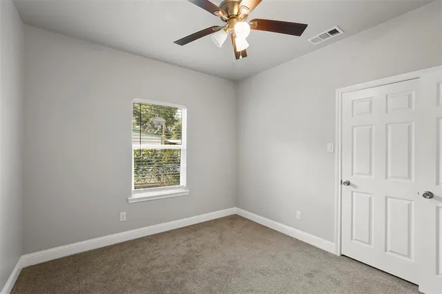 an empty room with a window and a fan