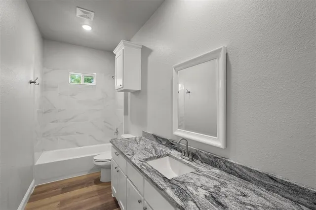 a bathroom with a granite countertop sink toilet and shower