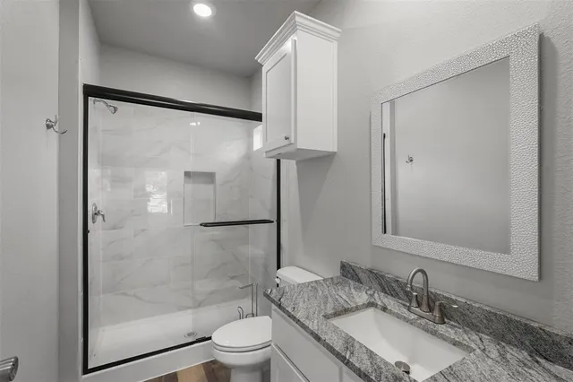 a bathroom with a granite countertop sink toilet and shower