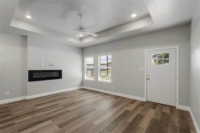 a view of an empty room with a window and wooden floor