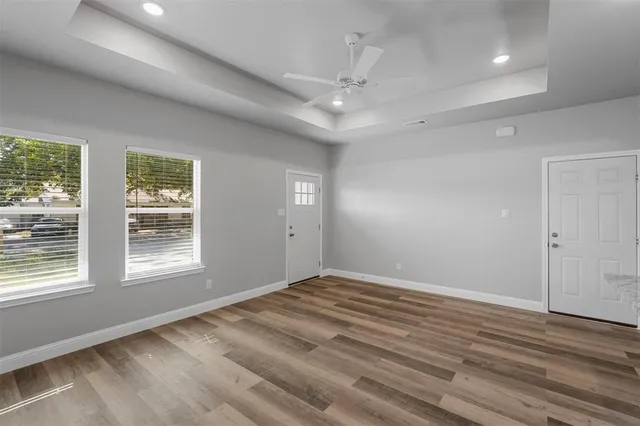 an empty room with wooden floor cabinet and windows