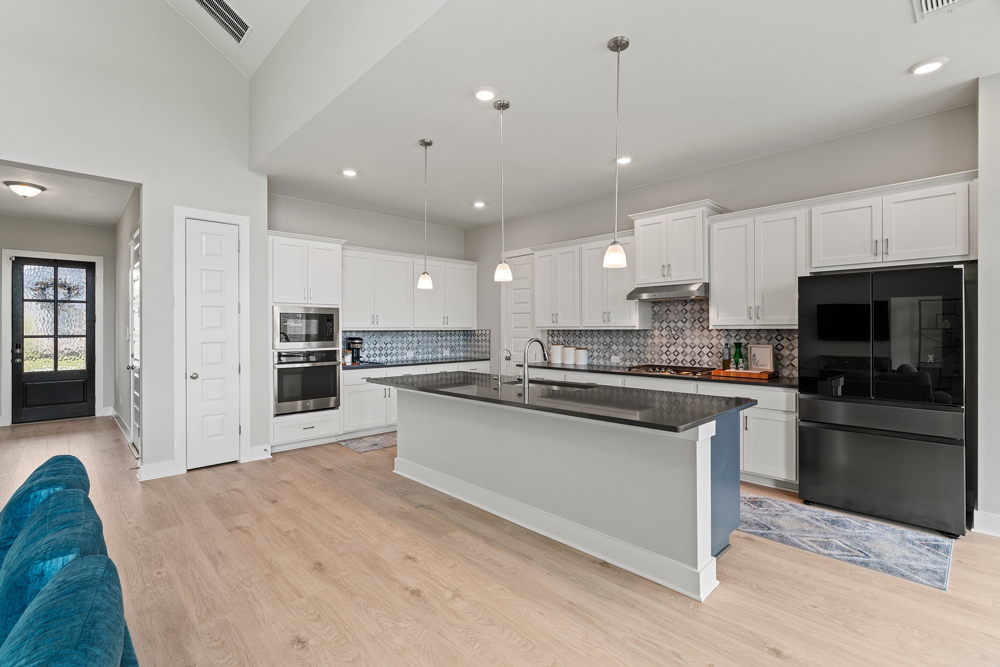 2112 Tobiano Trace Georgetown, TX 78633 - Photo 11 of 40 Kitchen with stainless steel appliances, a kitchen island with sink, white cabinetry, pendant lighting, and light wood-style floors