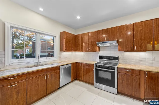 a kitchen with stainless steel appliances granite countertop a stove a sink and a microwave