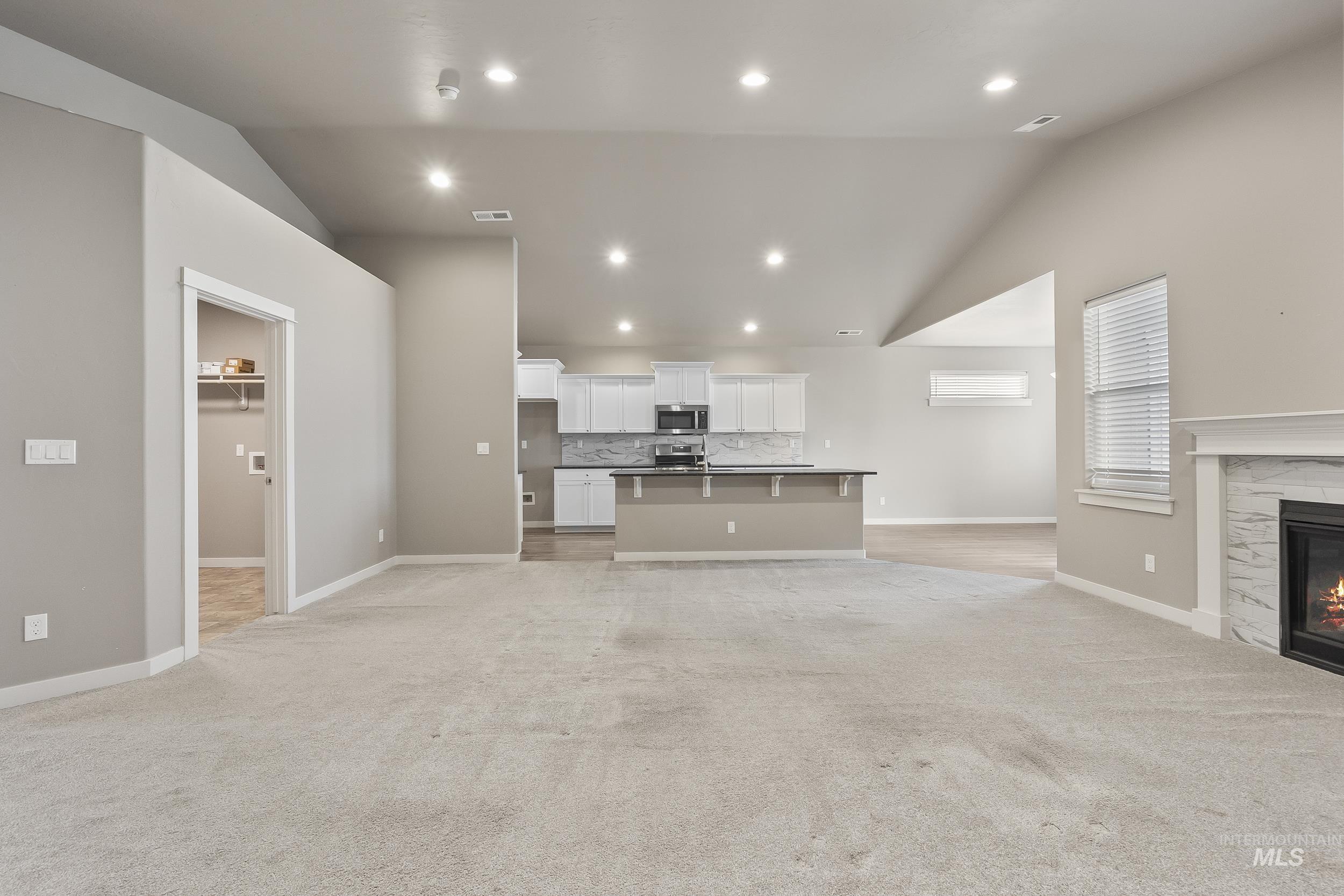 10308 West Trident Ridge Drive Star, ID 83669 - Photo 13 of 42 Unfurnished living room with a high end fireplace, light colored carpet, lofted ceiling, and recessed lighting