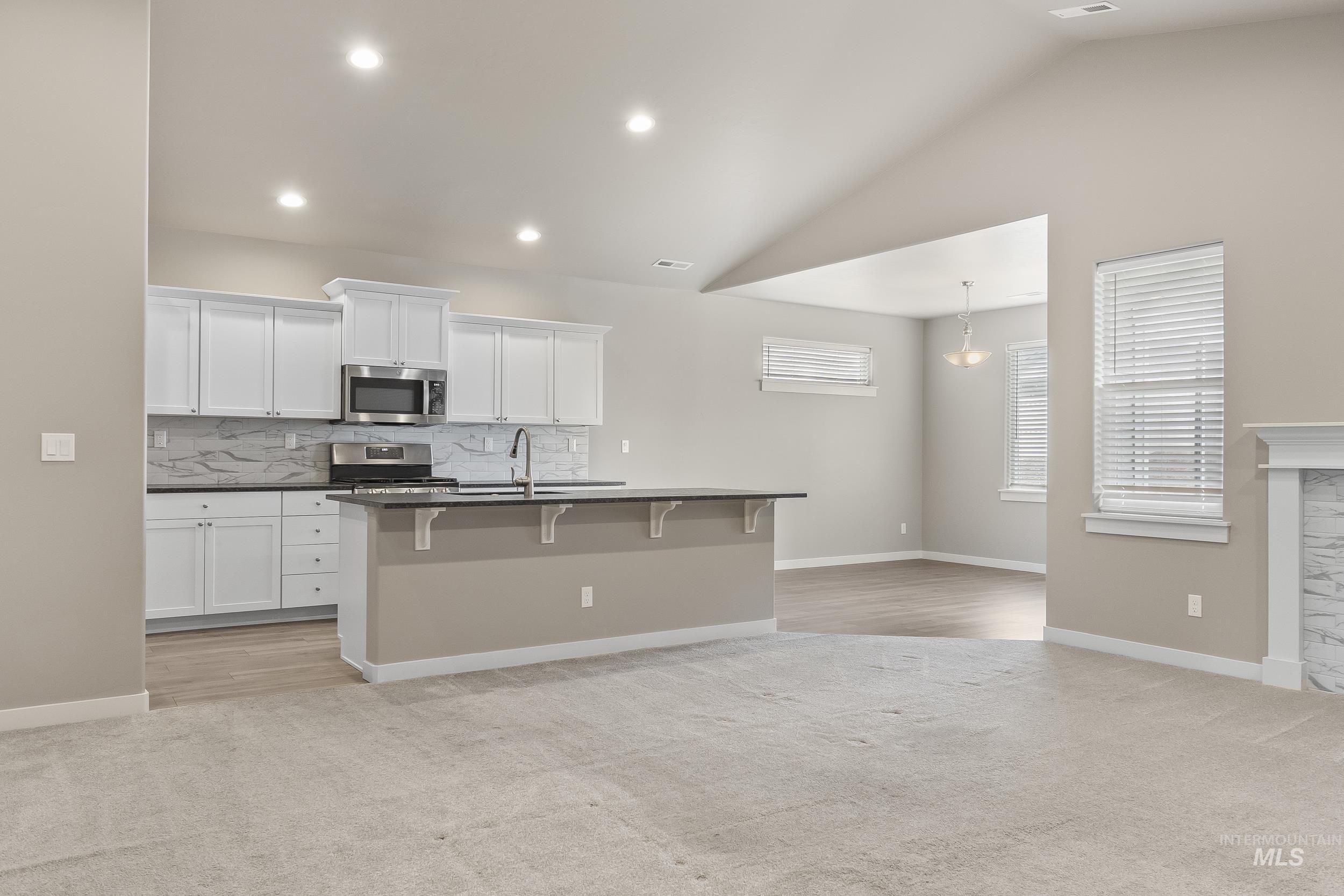 10308 West Trident Ridge Drive Star, ID 83669 - Photo 14 of 42 Kitchen with white cabinetry, tasteful backsplash, light colored carpet, stainless steel appliances, and a breakfast bar area