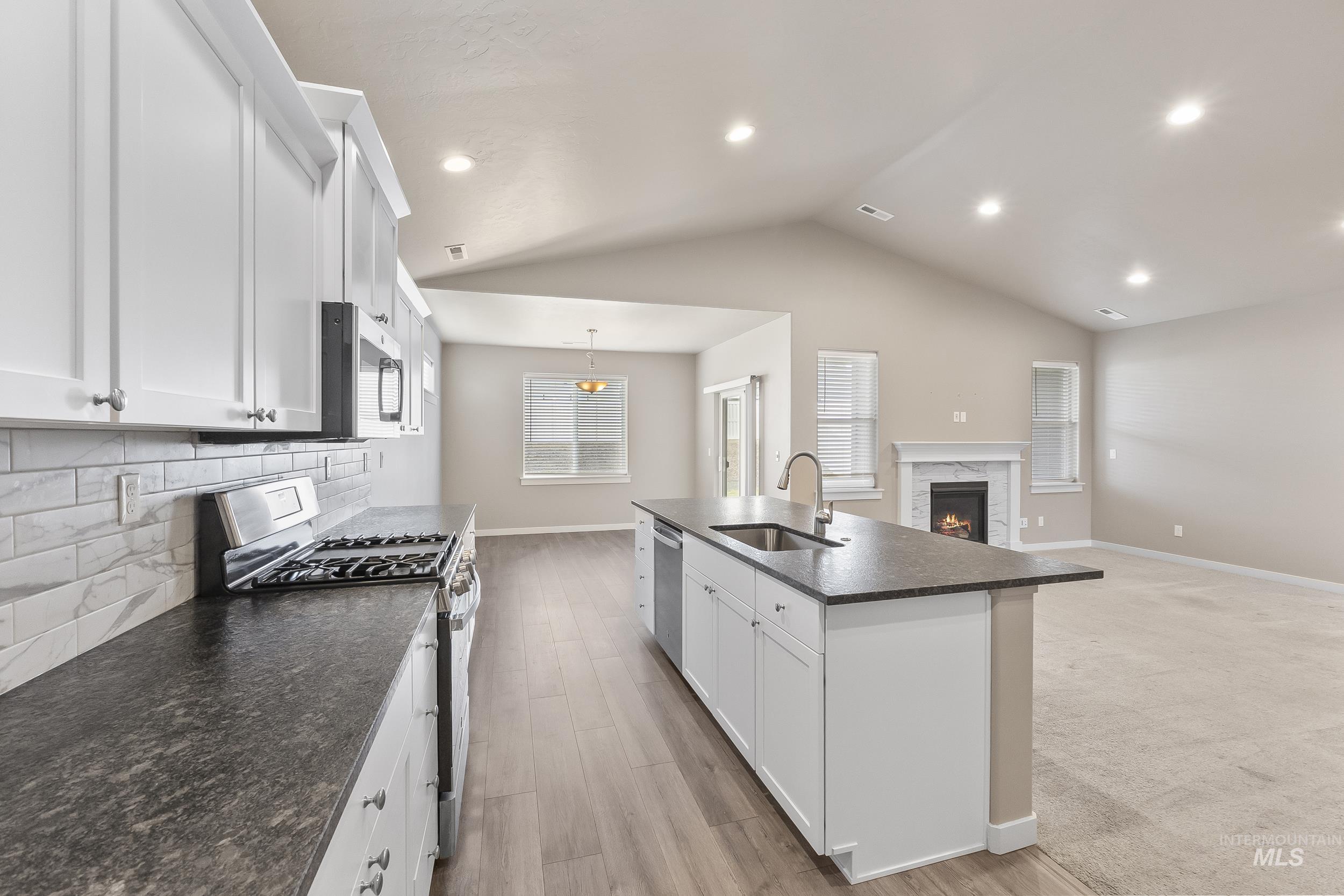 10308 West Trident Ridge Drive Star, ID 83669 - Photo 16 of 42 Kitchen with dark countertops, white cabinetry, stainless steel appliances, and a center island with sink