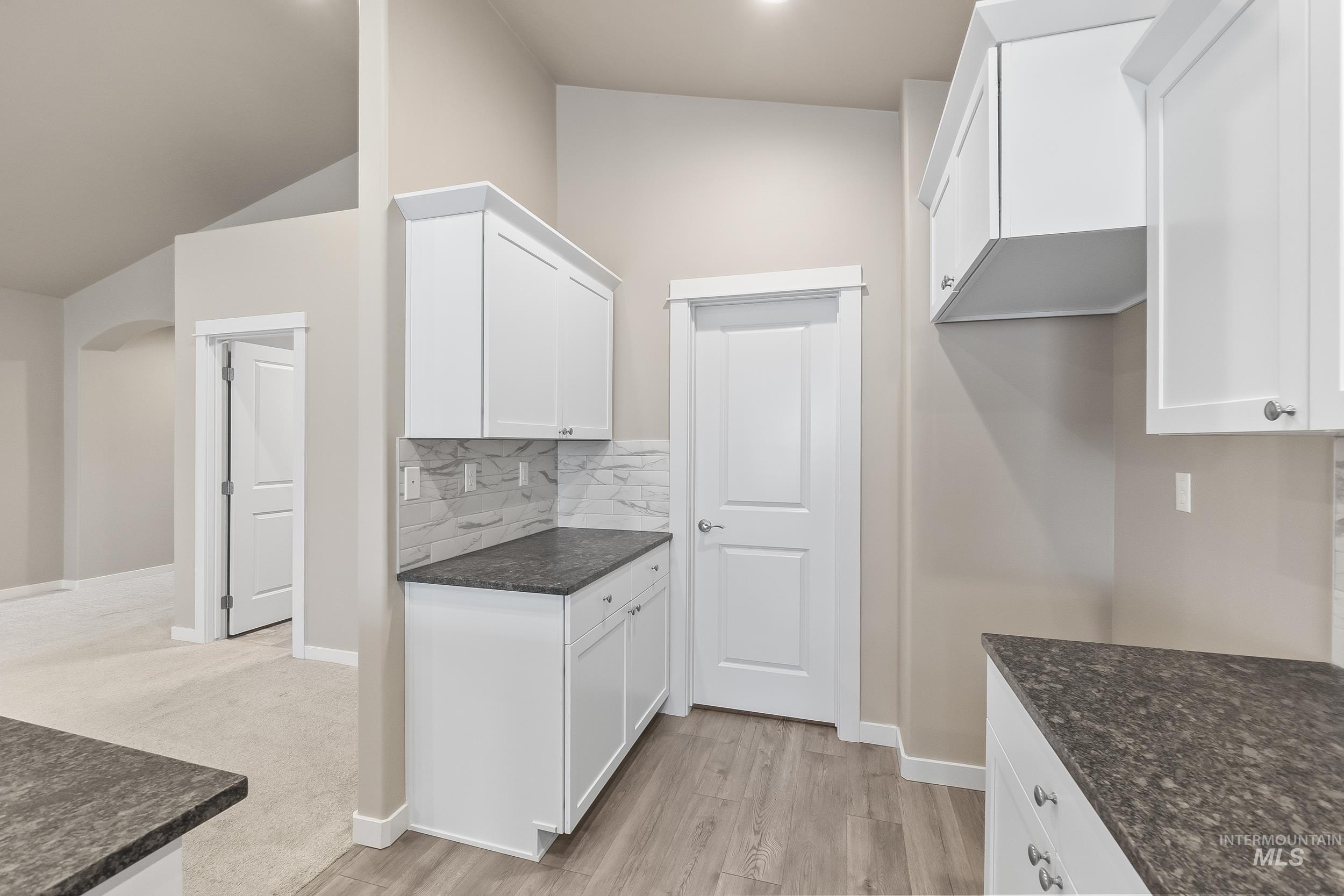 10308 West Trident Ridge Drive Star, ID 83669 - Photo 17 of 42 Kitchen with arched walkways, white cabinets, light wood-type flooring, and vaulted ceiling