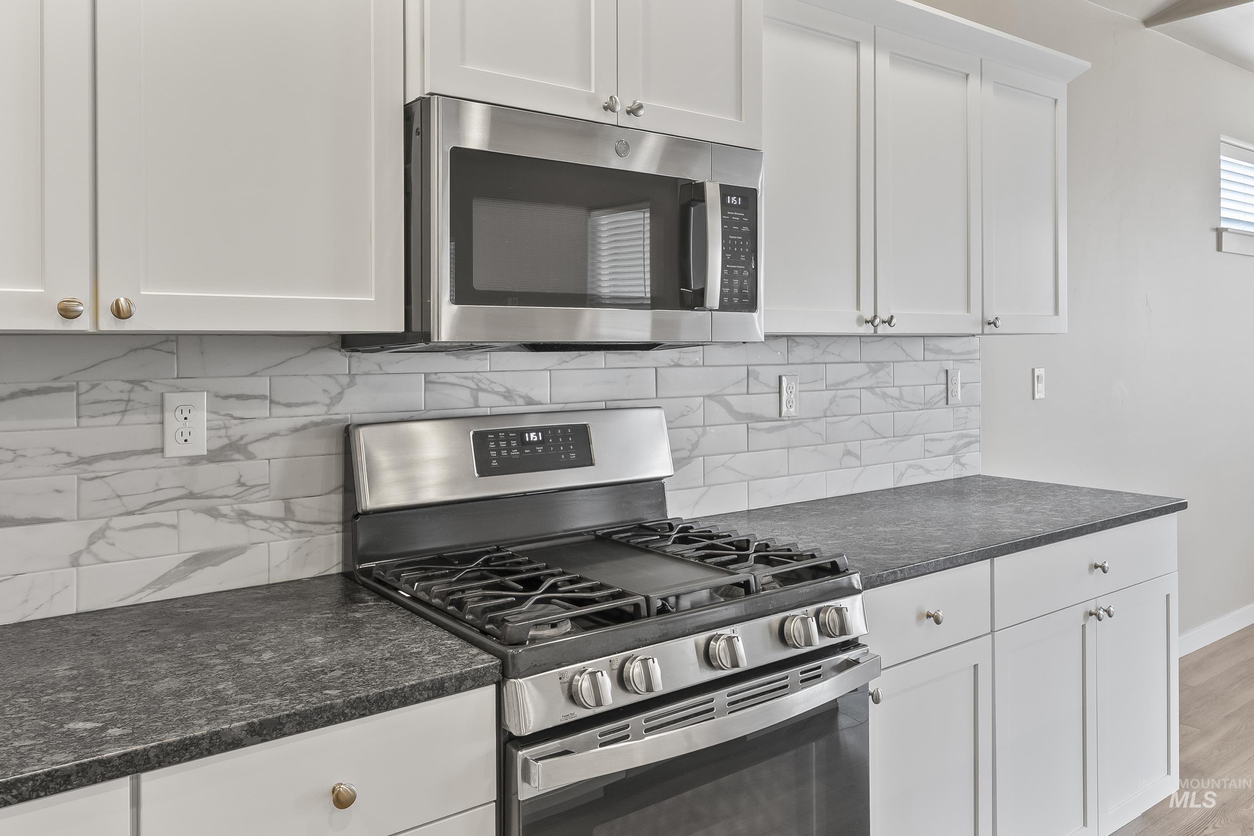 10308 West Trident Ridge Drive Star, ID 83669 - Photo 19 of 42 Kitchen with stainless steel appliances, white cabinetry, light wood-type flooring, and tasteful backsplash