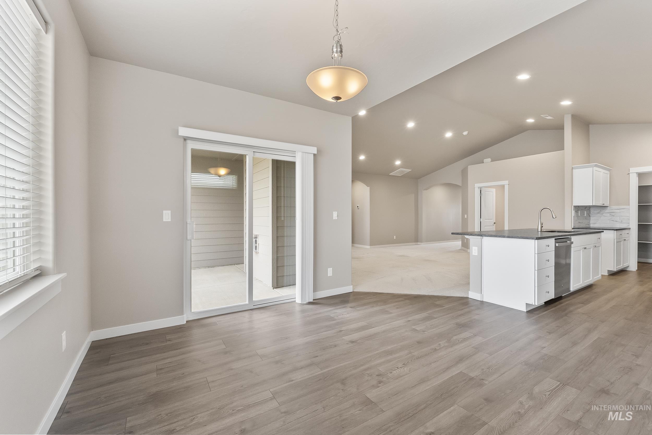 10308 West Trident Ridge Drive Star, ID 83669 - Photo 21 of 42 Kitchen with arched walkways, white cabinets, a peninsula, dark stone counters, and hanging light fixtures