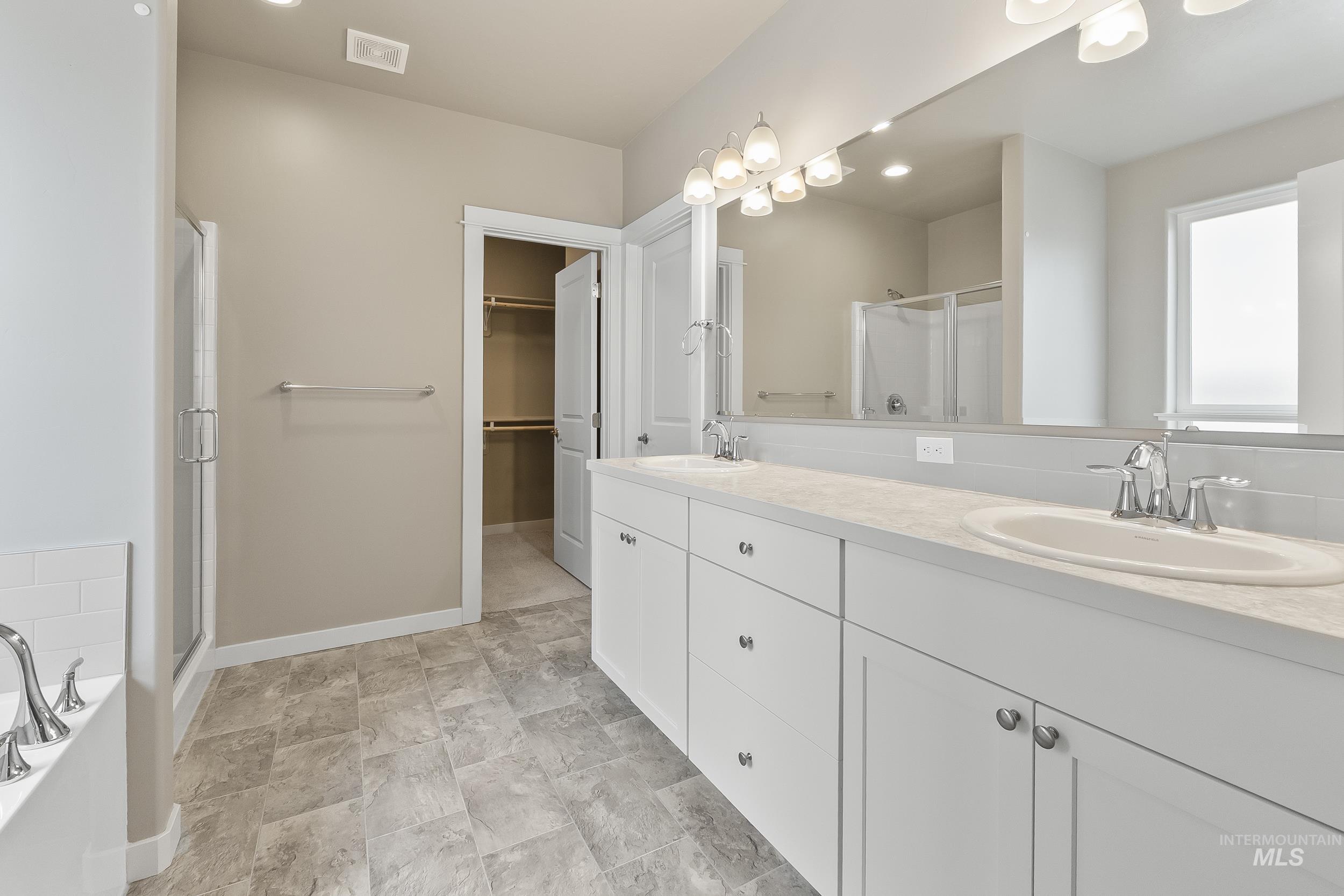 10308 West Trident Ridge Drive Star, ID 83669 - Photo 24 of 42 Bathroom featuring a stall shower, double vanity, a bath, stone finish flooring, and a spacious closet