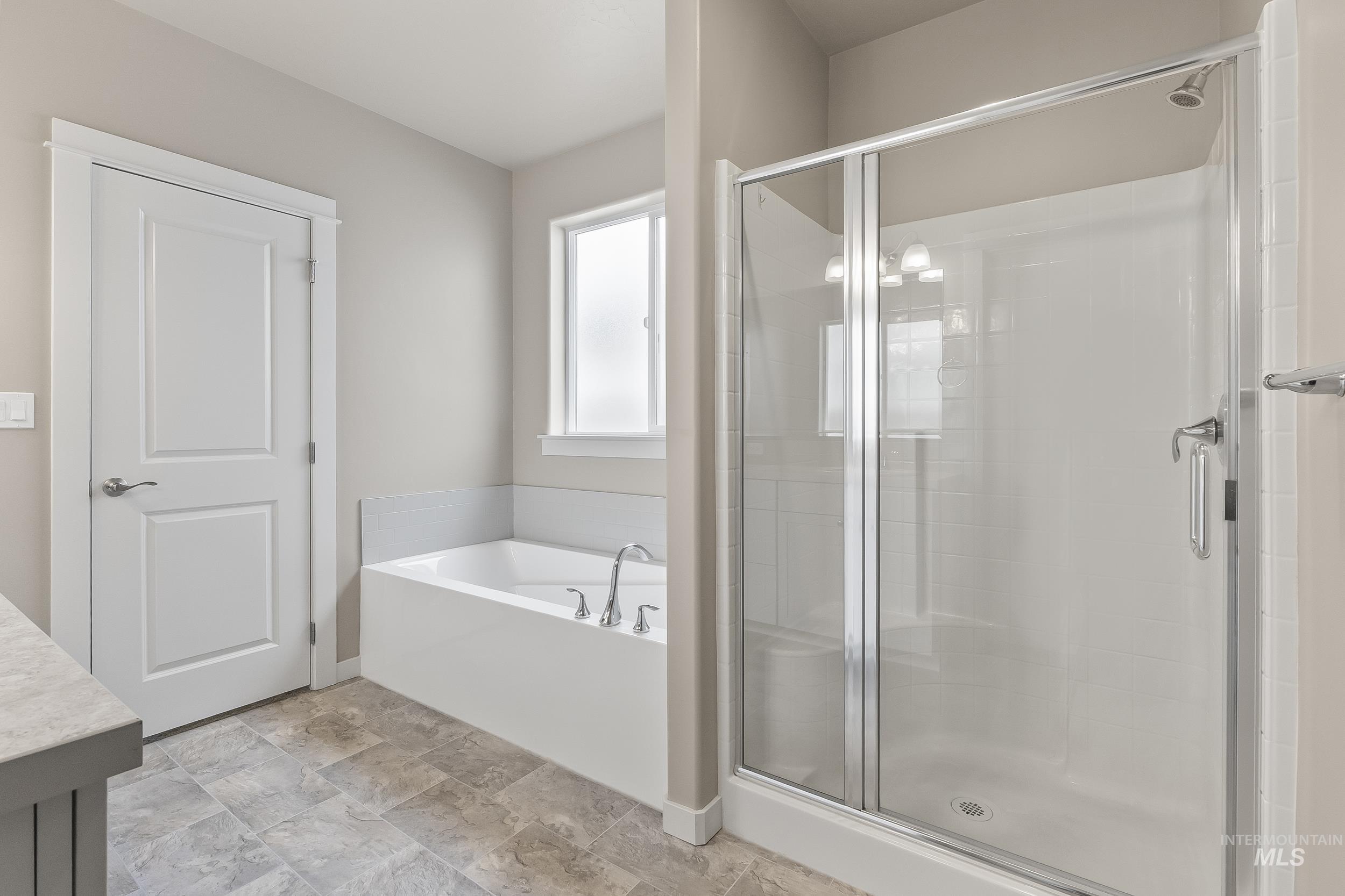 10308 West Trident Ridge Drive Star, ID 83669 - Photo 26 of 42 Bathroom with a stall shower, a garden tub, vanity, and stone finish flooring