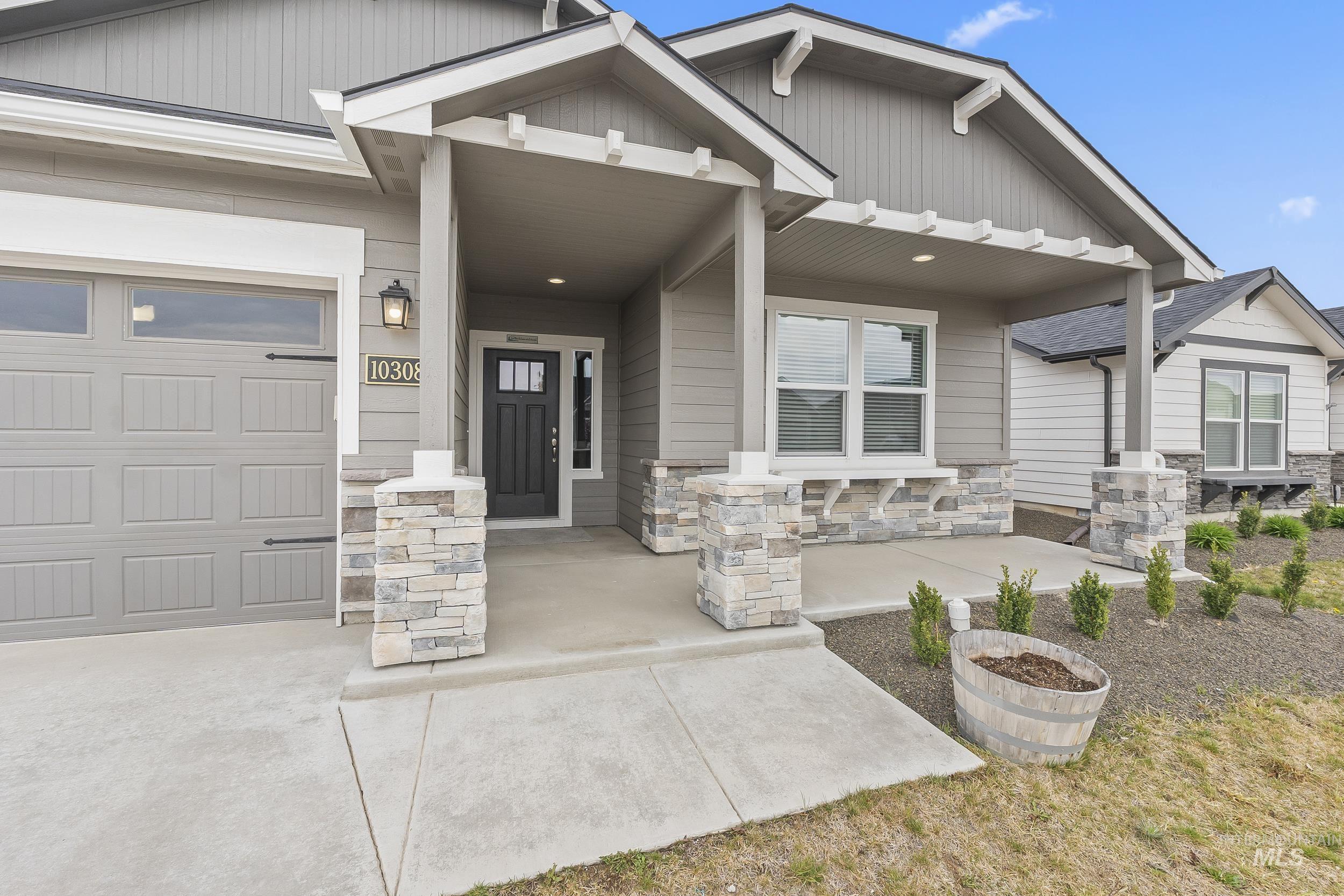 10308 West Trident Ridge Drive Star, ID 83669 - Photo 4 of 42 Entrance to property featuring stone siding, a porch, and an attached garage