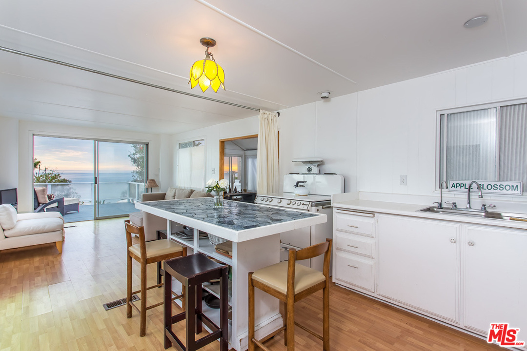 36 Copra Lane Pacific Palisades, CA 90272 - Photo 6 of 31 a kitchen with stainless steel appliances a table and chairs in it