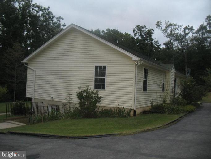 225 Barstow Road Prince Frederick, MD 20678 - Photo 10 of 10 a view of a white house next to a yard and large trees