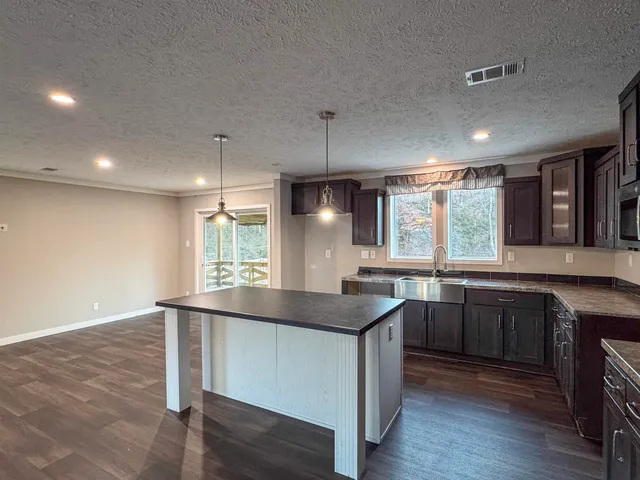 a kitchen with kitchen island stainless steel appliances a sink stove and wooden floor