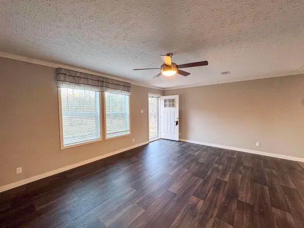 a view of an empty room with a window and wooden floor