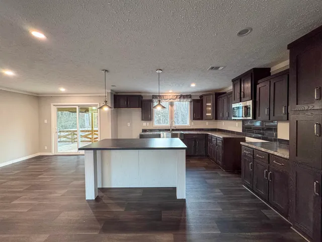 a kitchen with stainless steel appliances granite countertop wooden cabinets a sink dishwasher a stove and a refrigerator