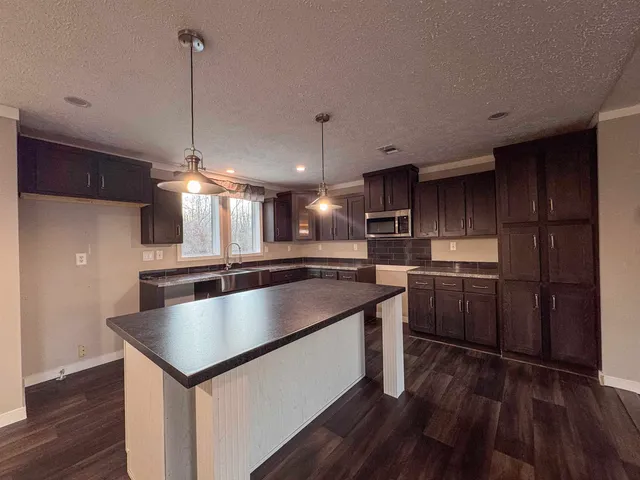 a kitchen with kitchen island a counter top space a sink and wooden floor