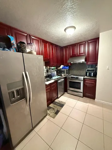 a kitchen with granite countertop a refrigerator and a stove top oven