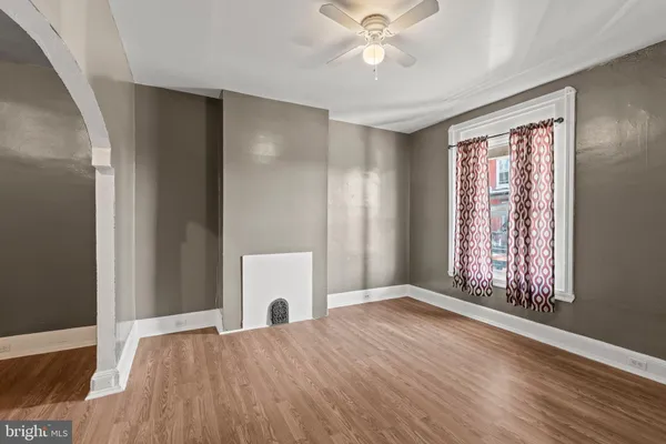 a view of an empty room with wooden floor and a window