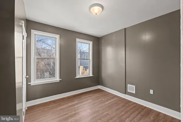 a view of an empty room with window and wooden floor