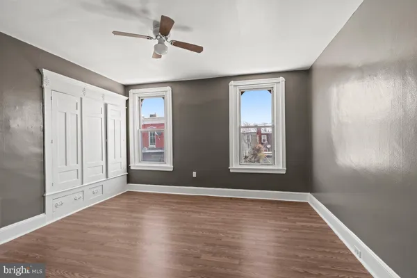 a view of an empty room with window and wooden floor