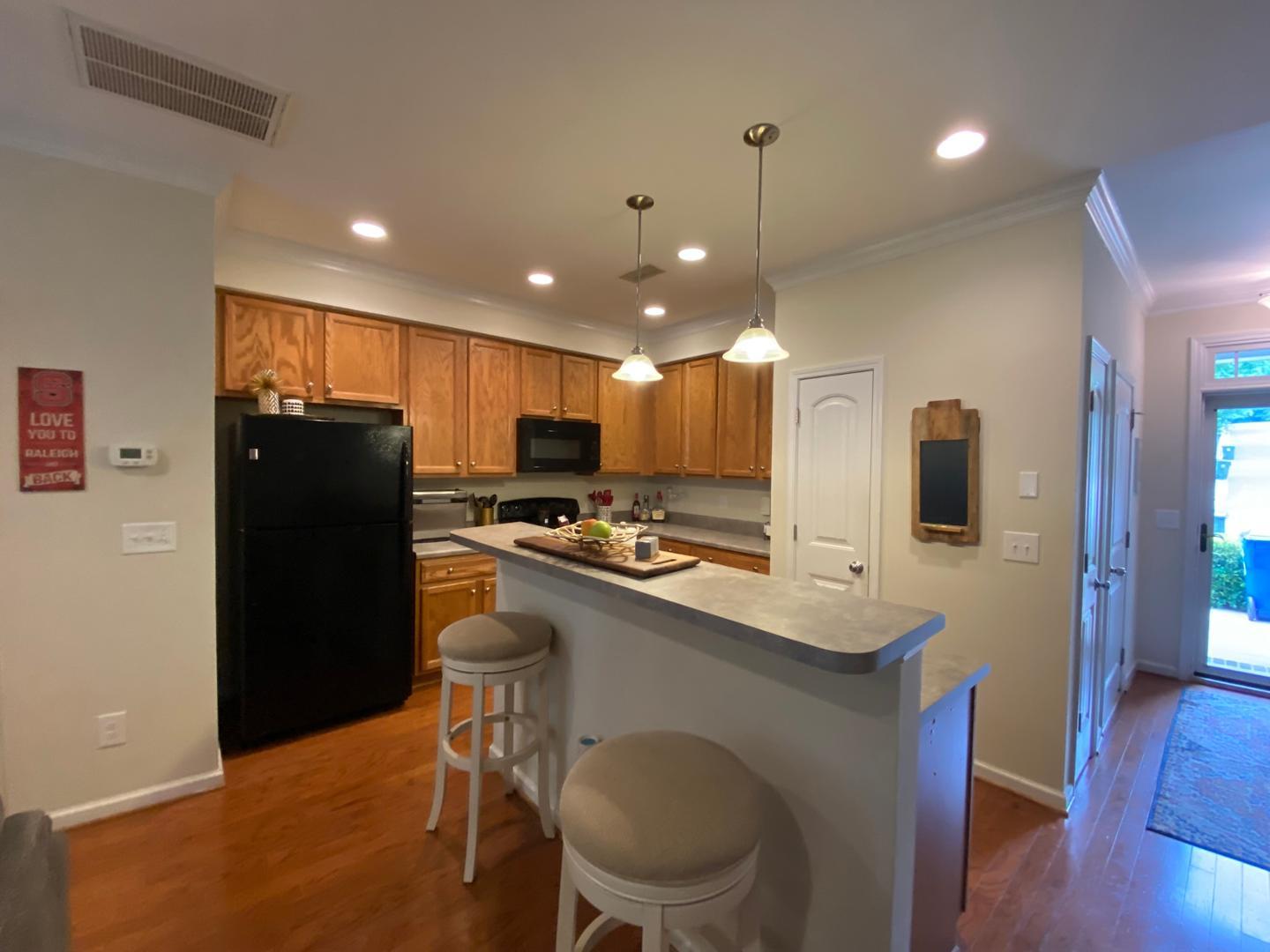 4646 Altha Street Raleigh, NC 27606 - Photo 6 of 23 a kitchen with a sink a refrigerator a stove and chairs